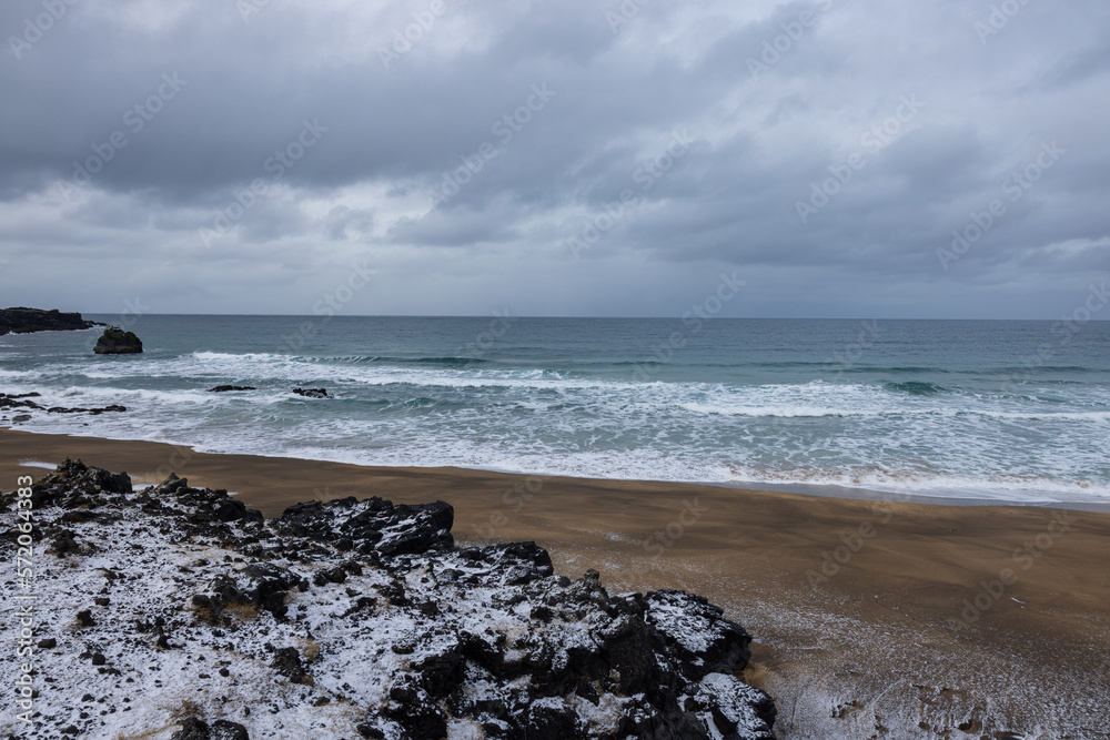 Fototapeta premium Great beach in Iceland where turquoise water meets golden sand and white snow.
