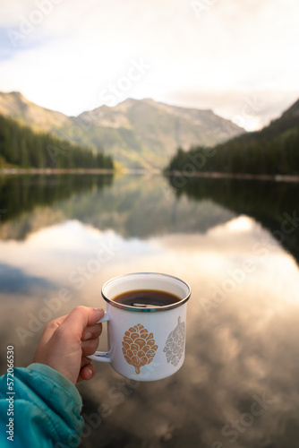 Hiker drinking coffee at alpine lake in Montana on a backpacking trip