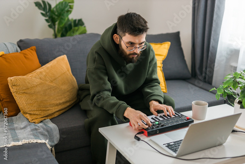 Canvas Print Man music producer or arranger using laptop and midi keyboard and other audio equipment to create music at home studio