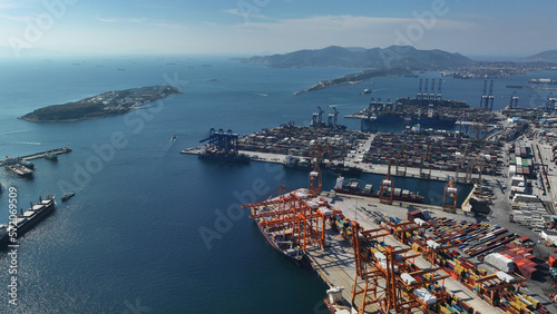 Aerial drone photo of huge fully loaded container tanker ship reaching with help of tug boat logistics and container terminal of Perama, Attica, Greece