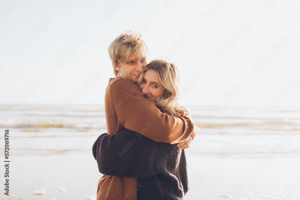 couple embracing with just the woman looking at the camera at the beach couple embracing with just the woman looking at the camera at the beach