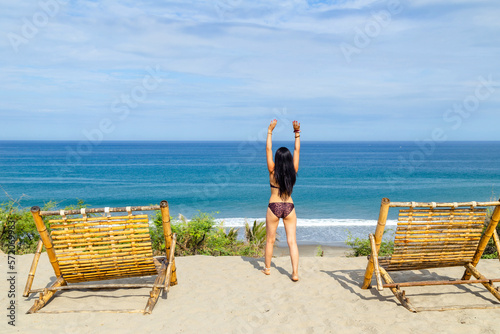 Girl raising her arms in front of the sea, relaxed and happy