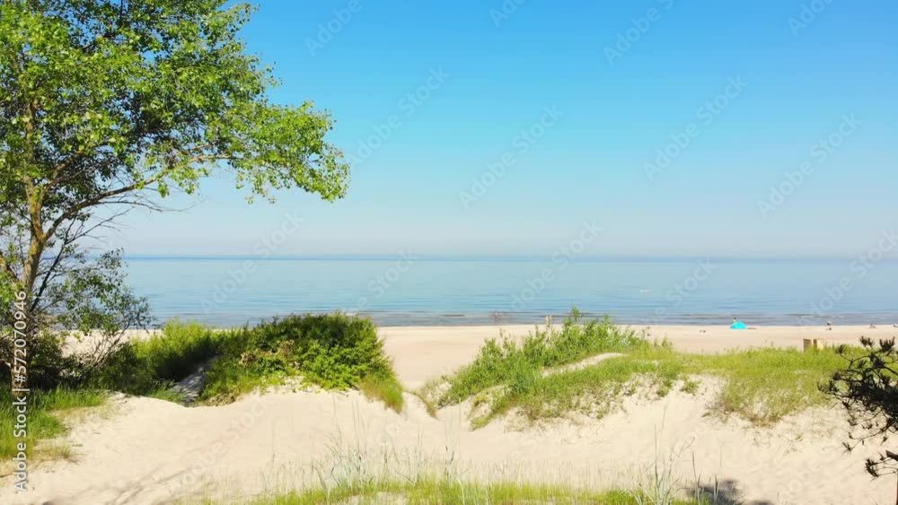 Zoom in view typical Baltic sea coast landscape beach view in Lithuania. Blue sky with no clouds, small waves in the sea and sand dunes partially overgrown with sedge grass Zoom in view typical Baltic sea coast landscape beach view in Lithuania. Blue sky with no clouds, small waves in the sea and sand dunes partially overgrown with sedge grass