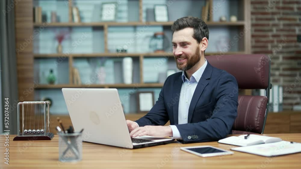 Happy mature business man investor in formal suit typing on laptop computer working online at desktop in modern office Smiling bearded entrepreneur enjoying great work day or good project indoors