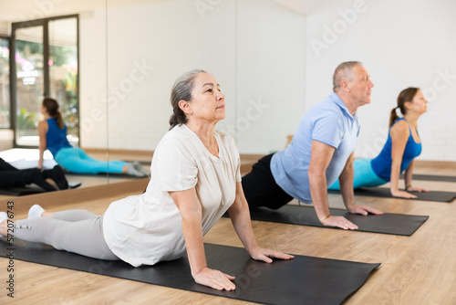 People of different ages performing cobra exercise during group Pilates workout. Active lifestyle and wellness concept