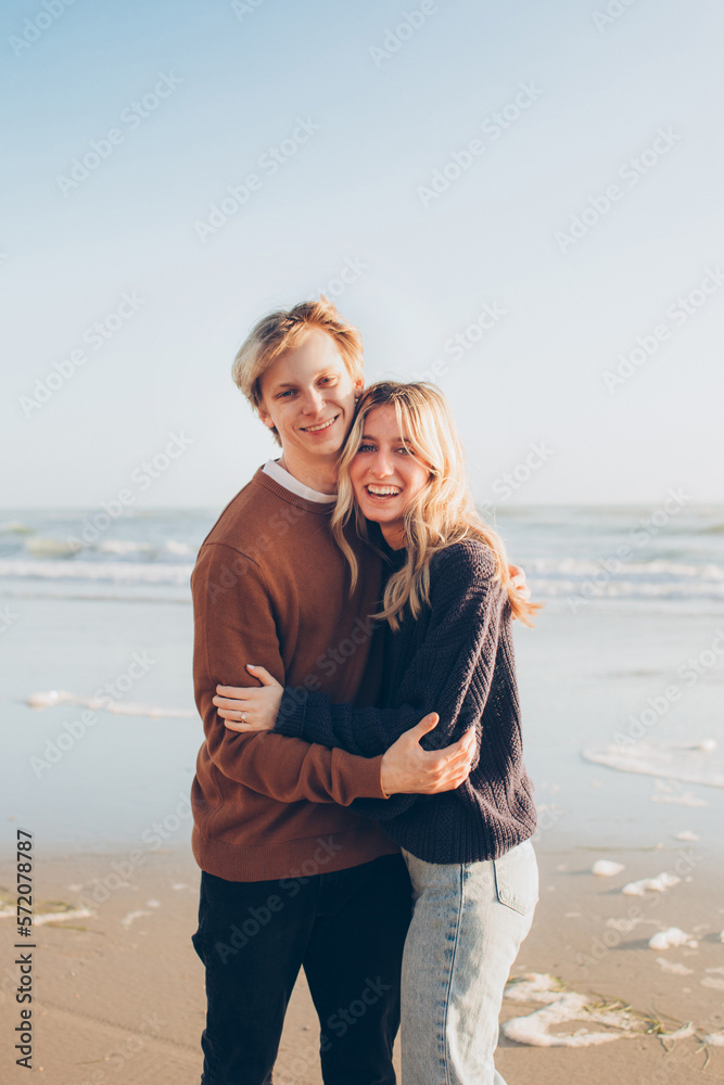 couple on the beach standing and smiling looking at the camera couple on the beach standing and smiling looking at the camera