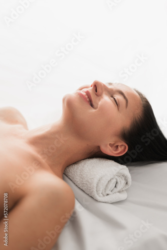 Happy relaxed woman lying on massage table with closed eyes