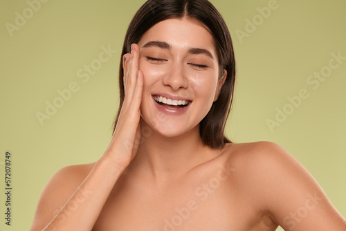 Happy young woman touching clean face