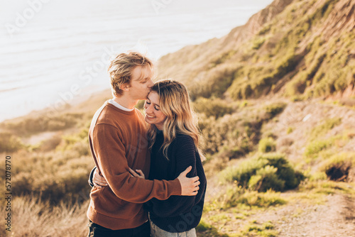 Foto couple embracing at the beach with him kissing her on the forehead