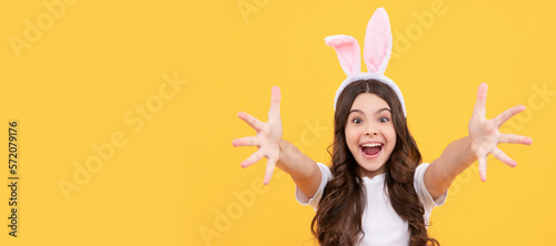 Canvas Print happy amazed kid in bunny ears reach hands on yellow background