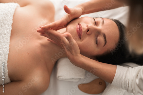 Massage therapist rubbing jaw of woman