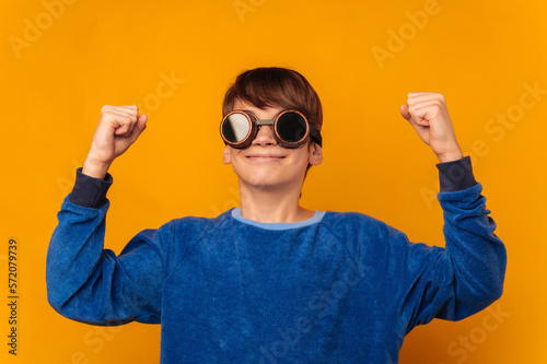 Adventurous teen boy makes the winner gesture while wearing pilot glasses.