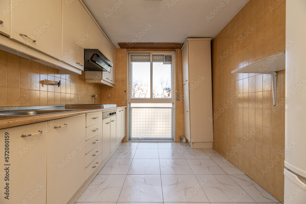 Kitchen furnished with a wall covered with cream-colored furniture with matching handles, stoneware floors, an aluminum bay window Kitchen furnished with a wall covered with cream-colored furniture with matching handles, stoneware floors, an aluminum bay window
