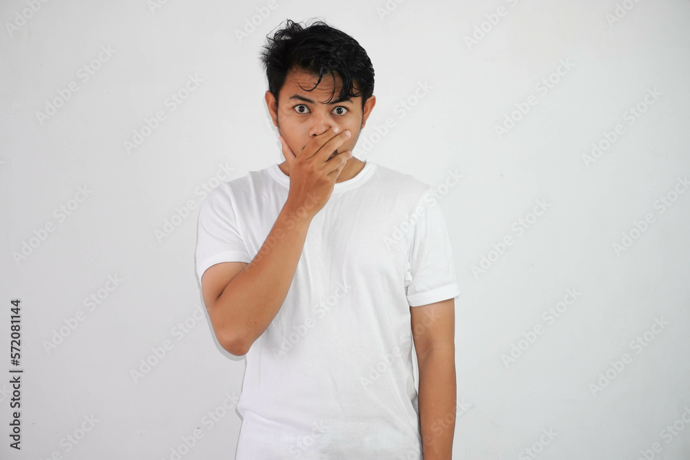 Portrait of scared young Asian man covering mouth with hands wearing white t shirt isolated on white background Portrait of scared young Asian man covering mouth with hands wearing white t shirt isolated on white background