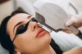 Laser cosmetology armpit hair removal. Beautiful woman client in glasses have fear of pain while doing procedure