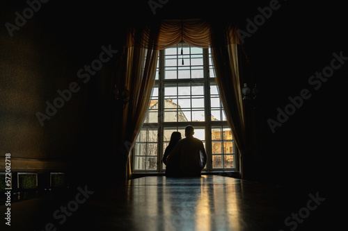 backlight of people near the window  the figure of young people near a large ancient window