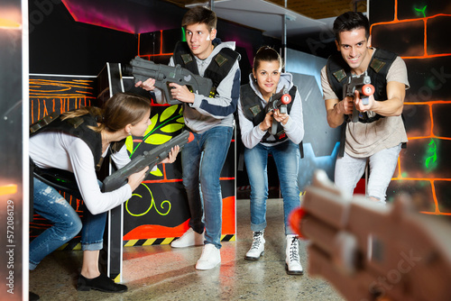 Modern young people with laser pistols playing laser tag on dark labyrinth..