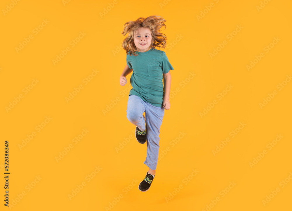 Energetic kid boy jumping and raising hands up on isolated studio background. Full length body size photo of jumping high child boy, hurrying up running fast on yellow background. Energetic kid boy jumping and raising hands up on isolated studio background. Full length body size photo of jumping high child boy, hurrying up running fast on yellow background.
