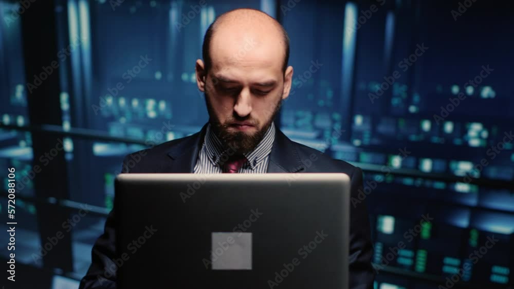 System administrator checking cluster computer service holding laptop in modern server room. Data center technician analyzing backup digitalization for networking industry. Handheld shot.