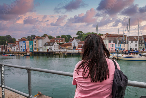  woman in focus enjoying the view of the bay with ships and boats of the seaside town Weymouth, England