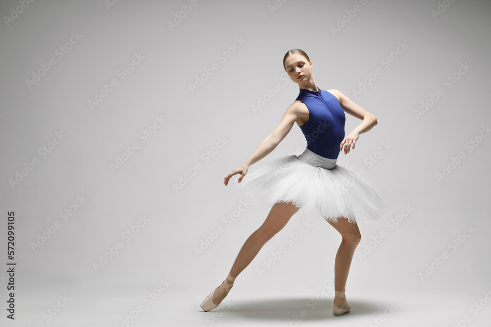 Young ballerina practicing dance moves on light grey background. Space for text