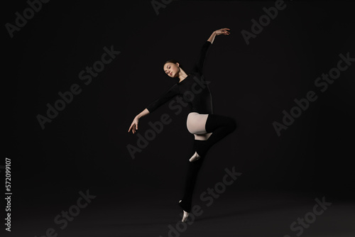 Young ballerina practicing dance moves on black background