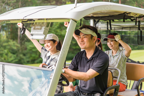 ゴルフ場でゴルフカートに乗るゴルファーの男女 撮影協力：あづみ野カントリークラブ
