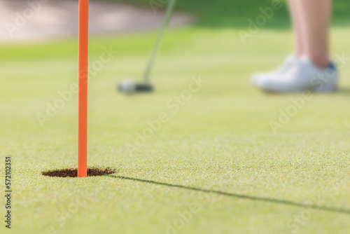 ゴルフ場のカップにパターを使ってホールインしようとする女性ゴルファー 撮影協力：あづみ野カントリークラブ