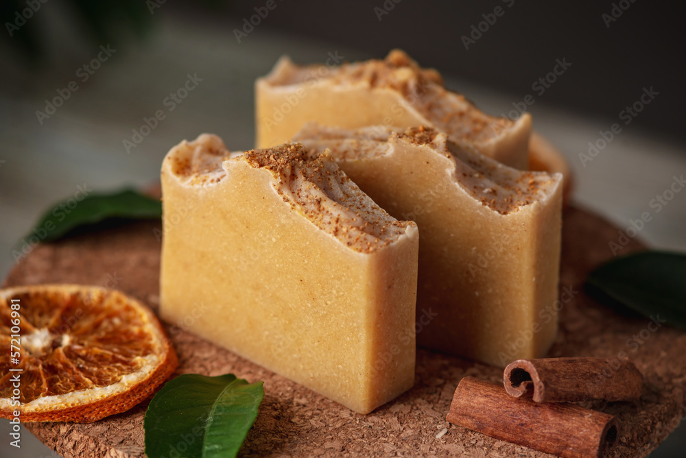 Piece of natural soap and slices of oranges, cinnamon and green leaves on the wooden table. Concept of eco cosmetics and hobby