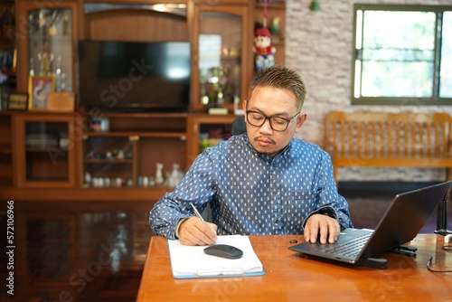 A middle-aged man was sitting at his desk writing a book.