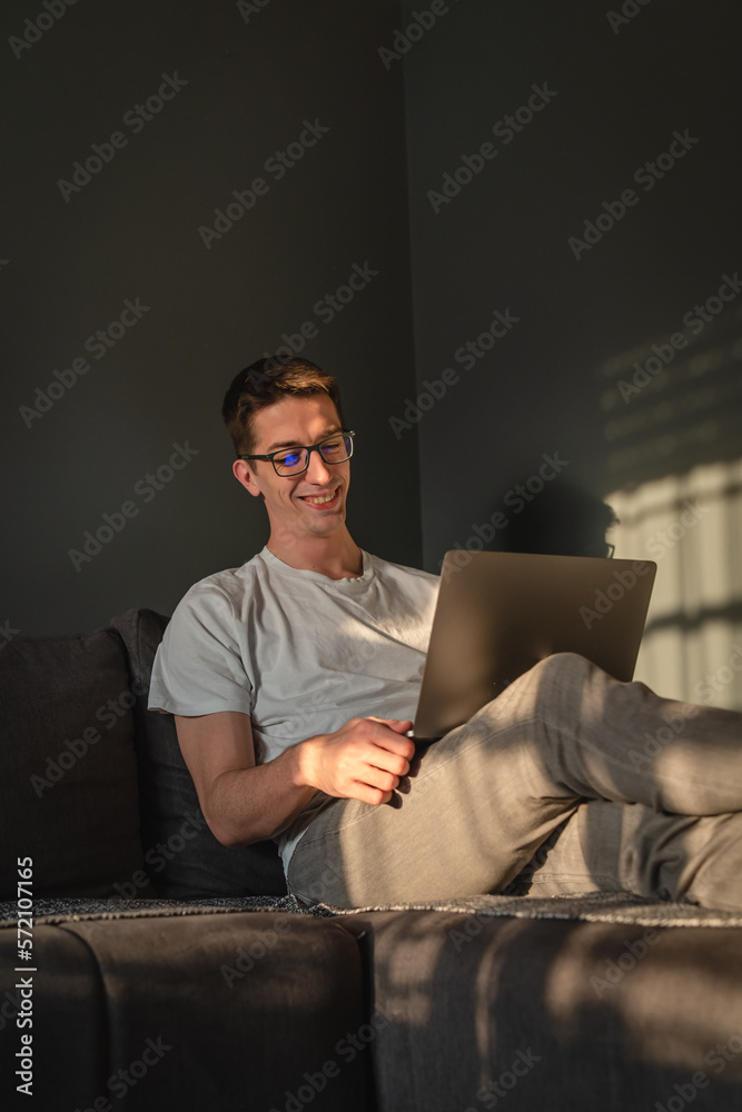 A young guy is laying on his bed while using laptop to study or to do business