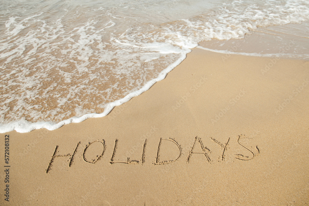 Fototapeta premium Holidays lettering on the beach with wave and clear blue sea.