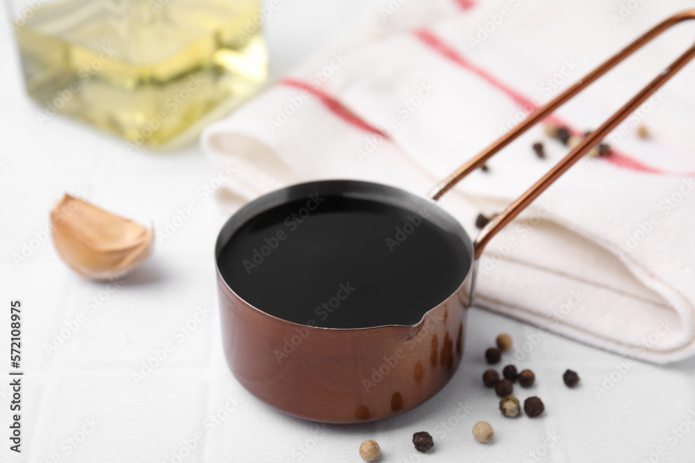 Metal small saucepan with balsamic vinegar and ingredients on white table Metal small saucepan with balsamic vinegar and ingredients on white table