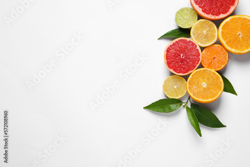 Different citrus fruits with fresh leaves on white background  top view. Space for text