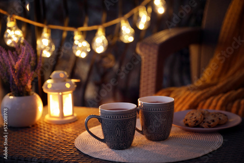Cups with tasty cocoa on rattan table at balcony in evening