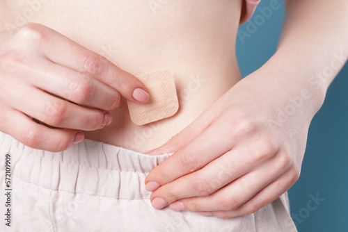 Wallpaper Mural Woman applying contraceptive patch onto her body on blue background, closeup Torontodigital.ca