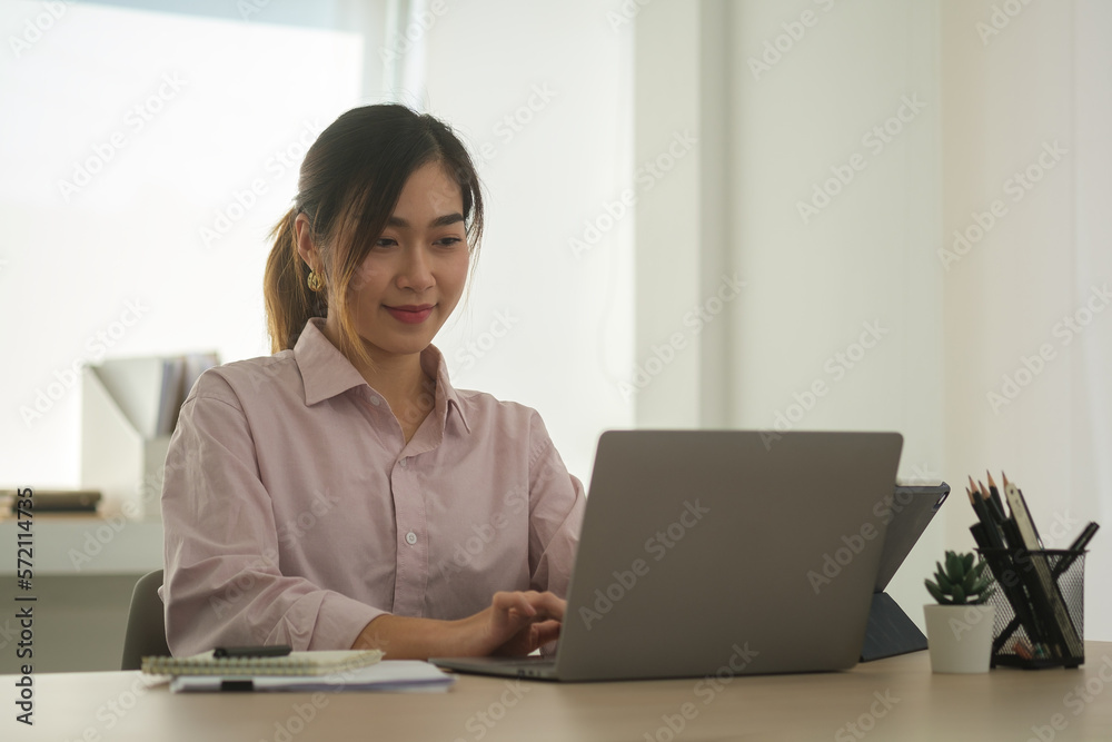 Pretty asian female employee using laptop at her office desk. Lifestyle, technology and wireless communication. Pretty asian female employee using laptop at her office desk. Lifestyle, technology and wireless communication.