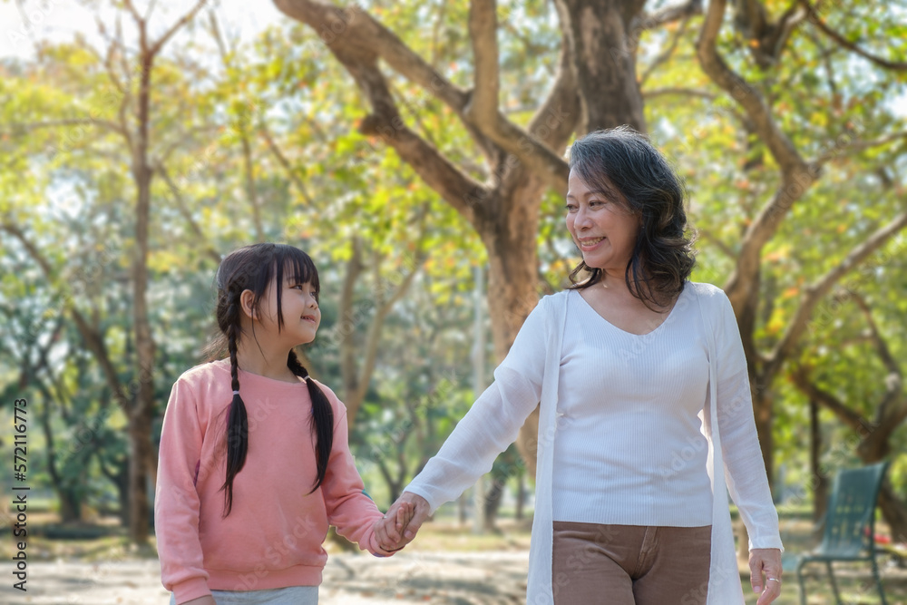 Active grandmother holding hands little granddaughter walking in the park enjoy priceless time together at funny weekend activities concept