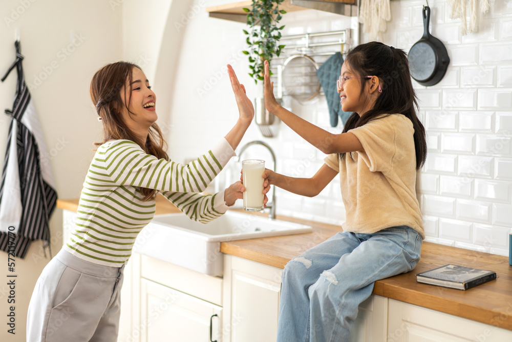 Portrait of enjoy happy love asian family mother with little asian girl smiling and having protein breakfast drinking and hold glasses of milk on counter in kitchen at home.Diet concept.healthy drink Portrait of enjoy happy love asian family mother with little asian girl smiling and having protein breakfast drinking and hold glasses of milk on counter in kitchen at home.Diet concept.healthy drink