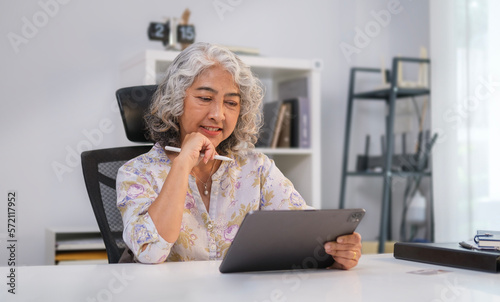 Elegant middle aged businesswoman with a natural friendly smile using digital tablet at office.