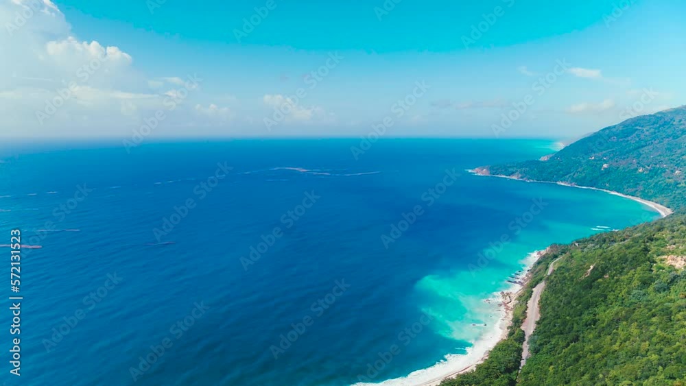Landscape of a tropical crooked island from a bird's eye view. Green hills against the blue sea. Mountain road along the steep coast. The beauty of the wild nature of the Dominican Republic. Landscape of a tropical crooked island from a bird's eye view. Green hills against the blue sea. Mountain road along the steep coast. The beauty of the wild nature of the Dominican Republic.