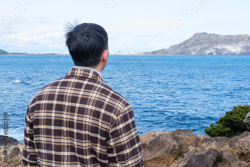 Portrait of a man looking at sea and mountain, back view.