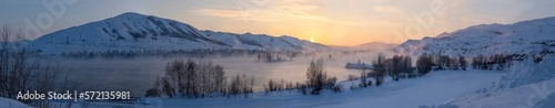 Panoramic winter view of the mountains in the snow and at sunset the river in the fog