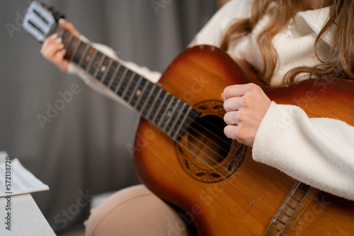 Woman playing acoustic guitar at home, female hands with guitar