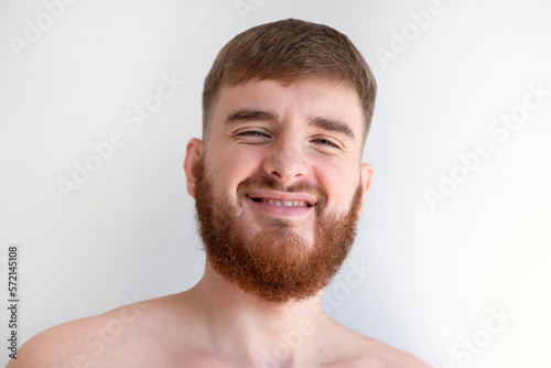 Portrait of bearded happy young handsome man with beard is smiling on white background and looking at camera