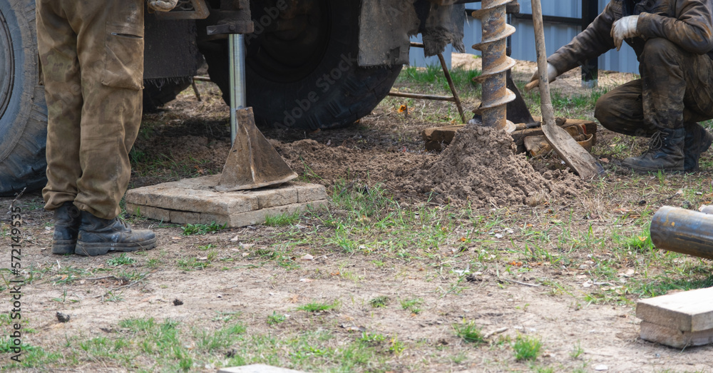 Team of workers with drilling rig on car are drilling artesian well for