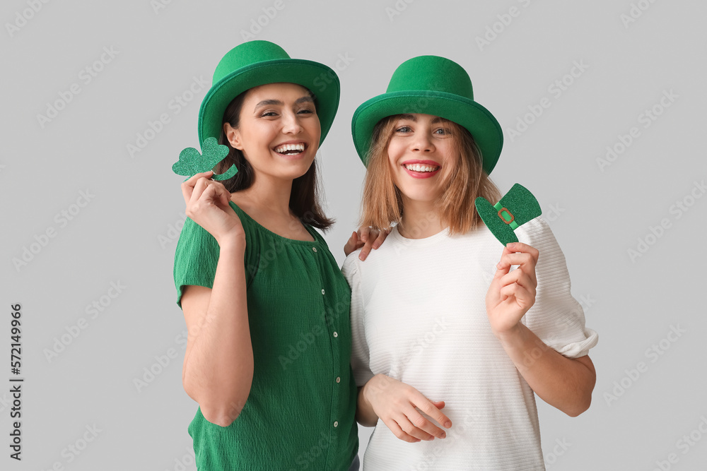 Young women with paper hat and clover on light background. St. Patrick's Day celebration Young women with paper hat and clover on light background. St. Patrick's Day celebration