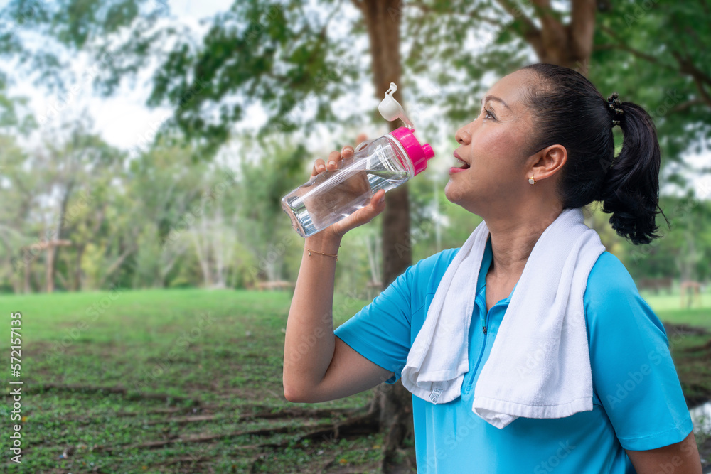 Senior woman drinking water after jogging in the park, exercise for health concept Senior woman drinking water after jogging in the park, exercise for health concept