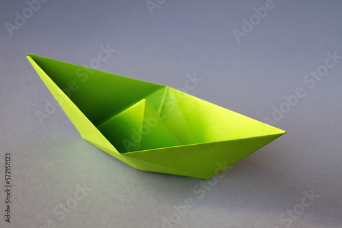 Green paper boat origami isolated on a grey background