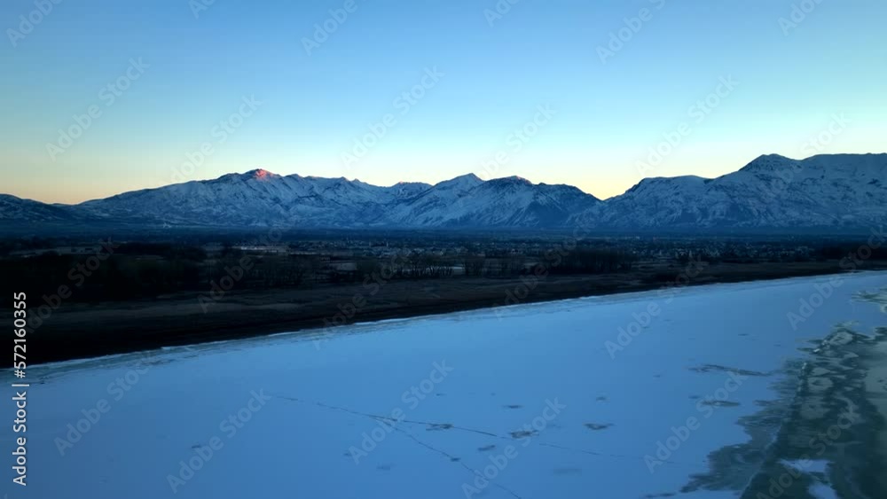 Snowy mountains in predawn light - aerial pull back to reveal a frozen lake Snowy mountains in predawn light - aerial pull back to reveal a frozen lake